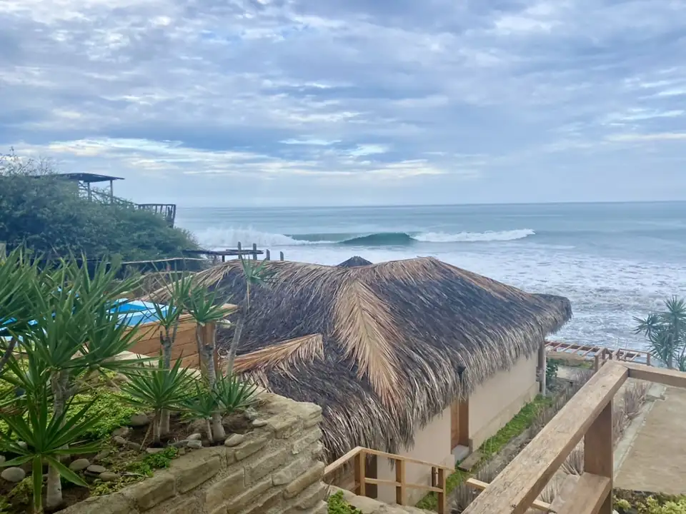 Techos de palma, senderos de madera y plantas costeras de La Playa frente a las olas del Pacífico.