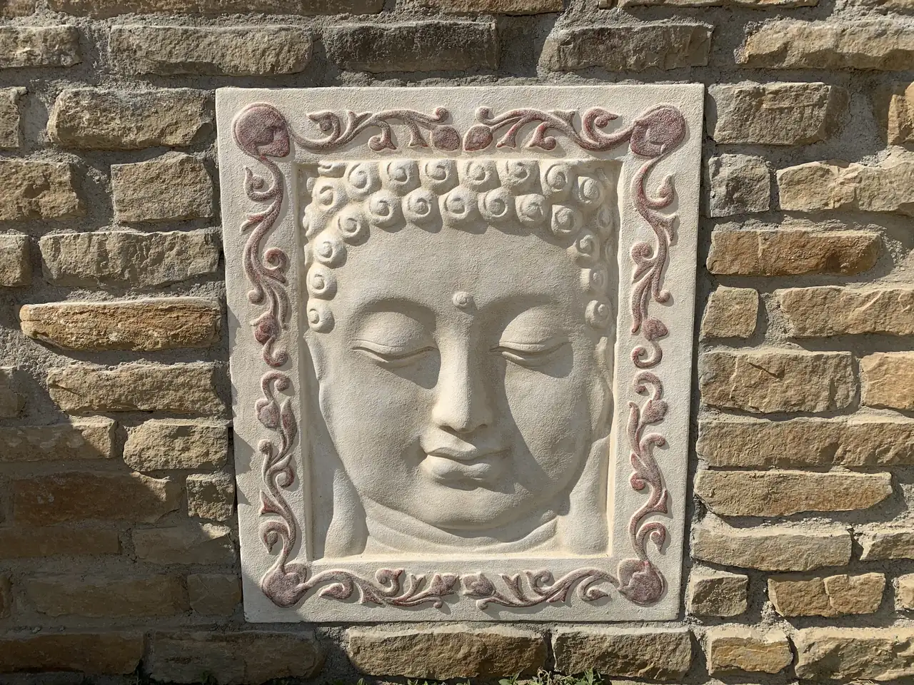 Relieve decorativo de Buda sobre un muro de piedra natural en La Playa.
