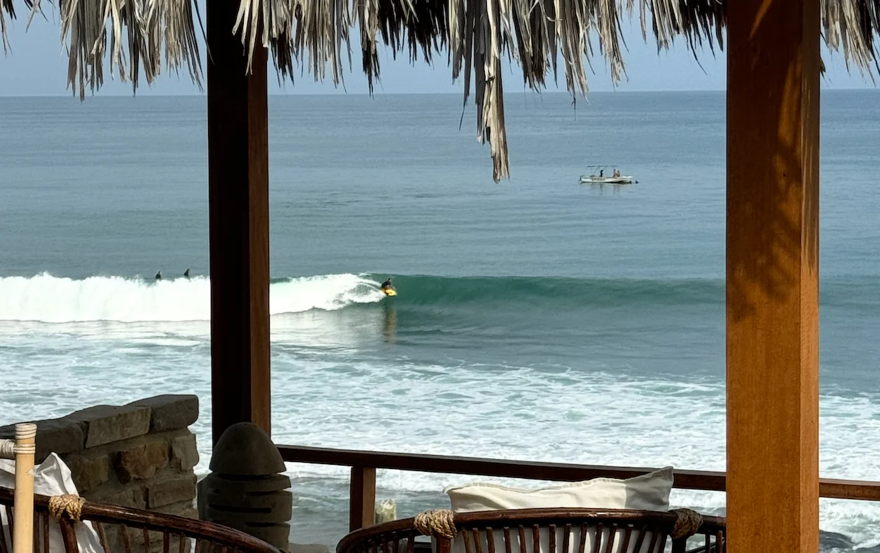 Un surfista sobre una ola, visto desde la terraza frente al mar de La Playa.